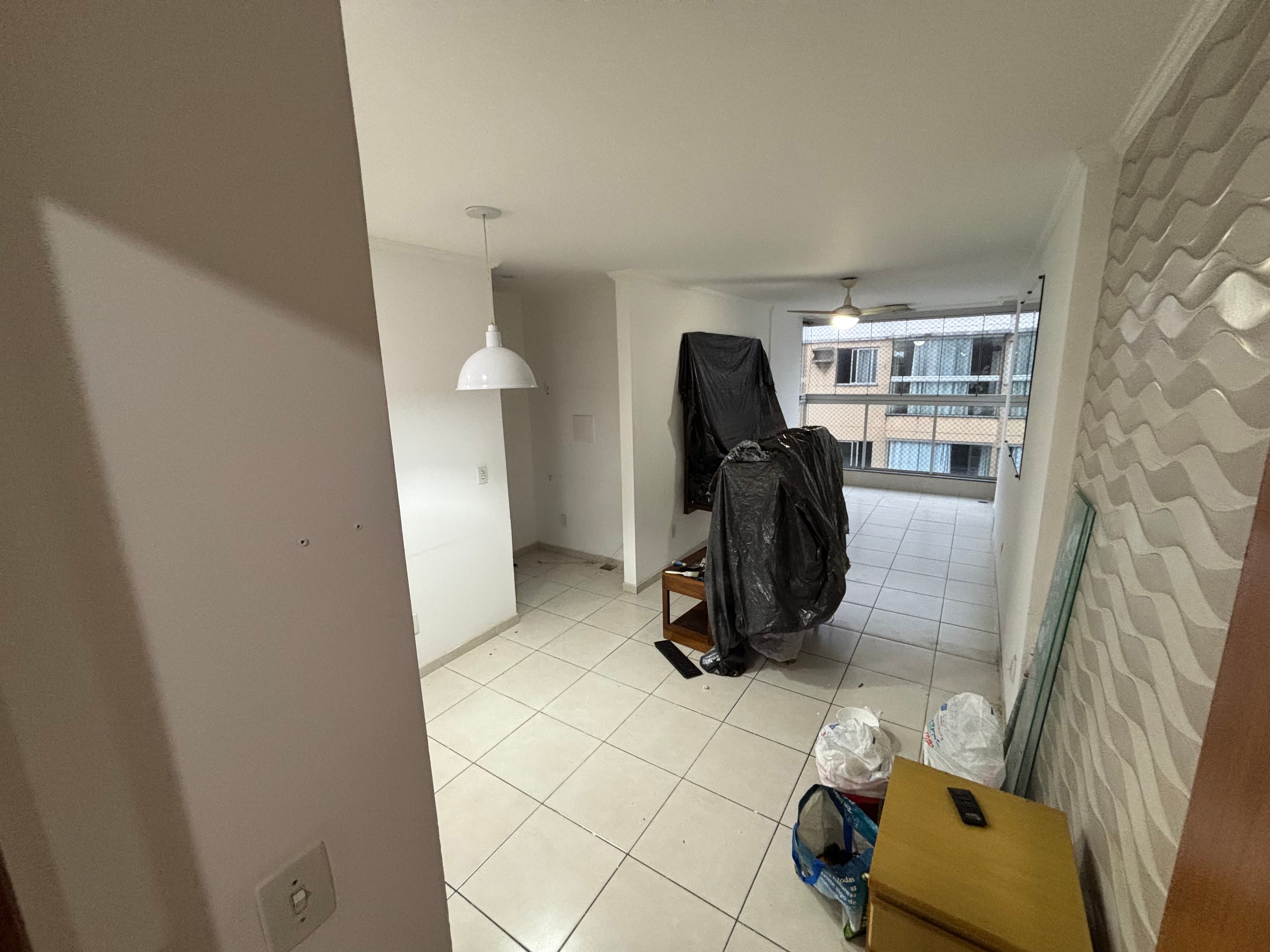 Sala integrada à varanda do apartamento em Itapuã, com porta de vidro