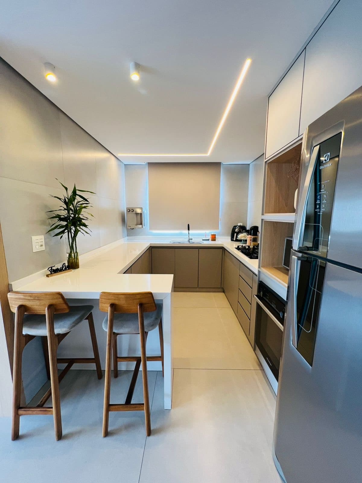 Bancada da cozinha com banquetas altas e geladeira embutida