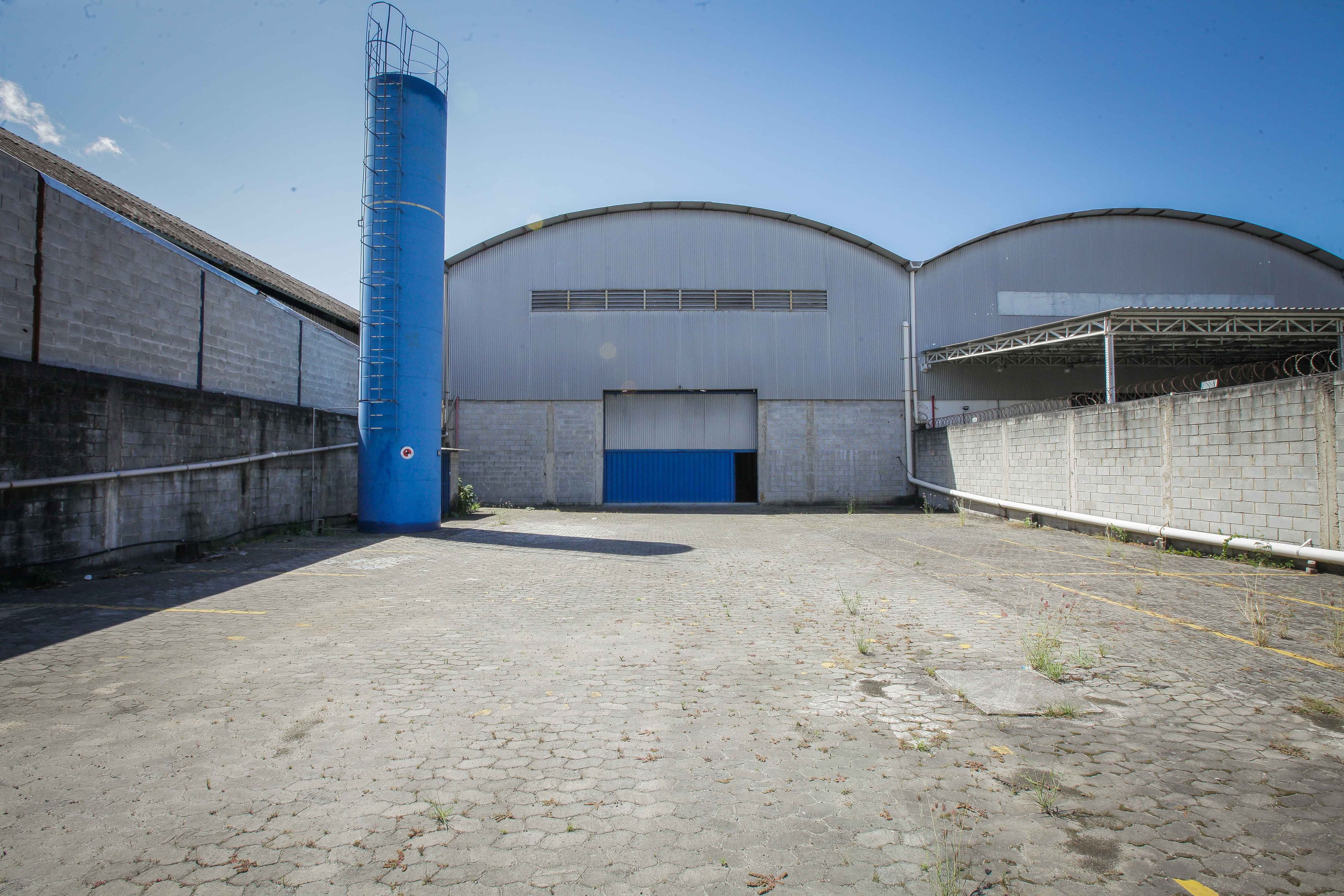 Fachada frontal do galpão com portão de acesso e pátio pavimentado
