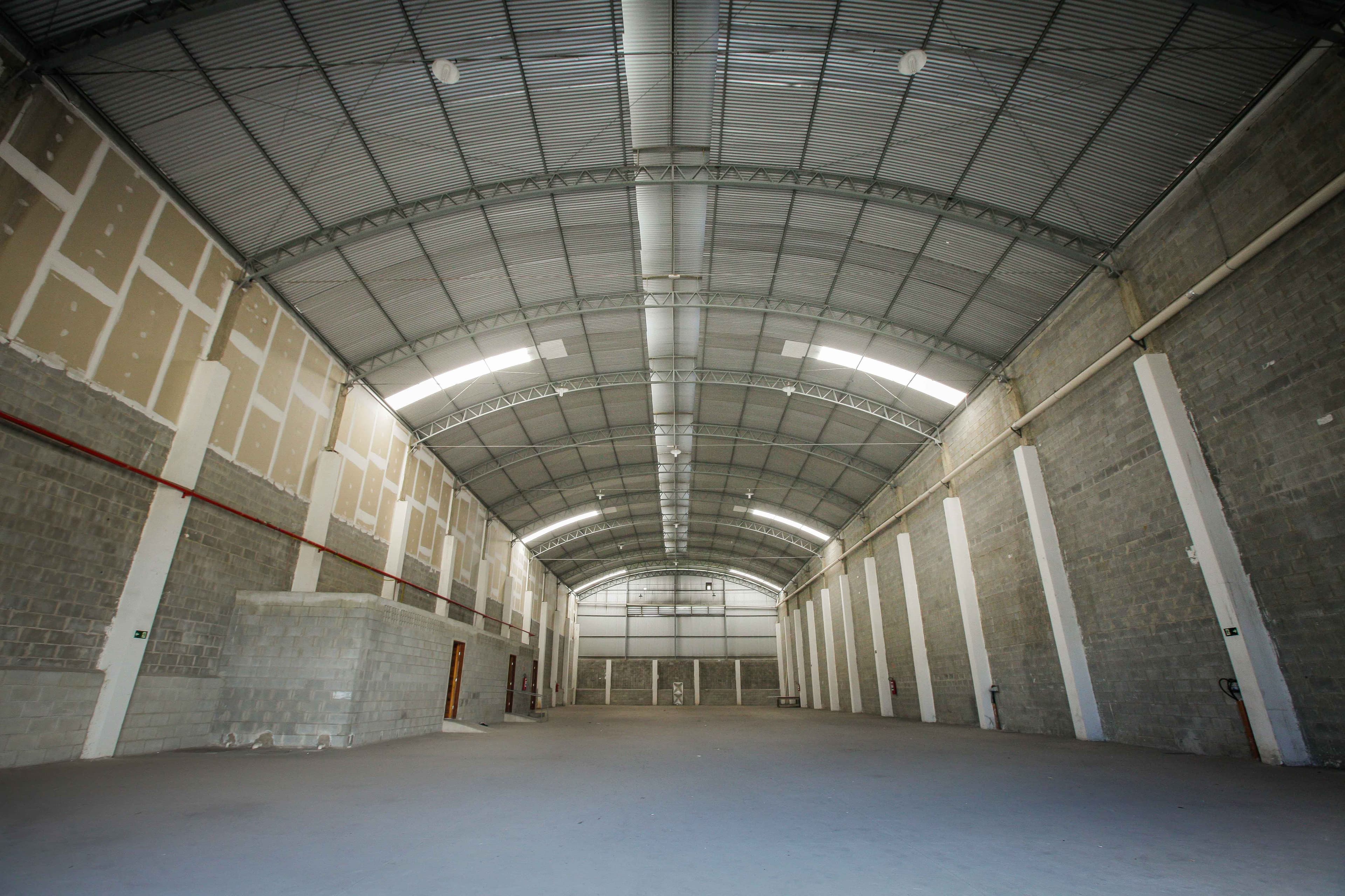 Interior do galpão em toda a extensão, com estrutura de cobertura em arco e iluminação linear