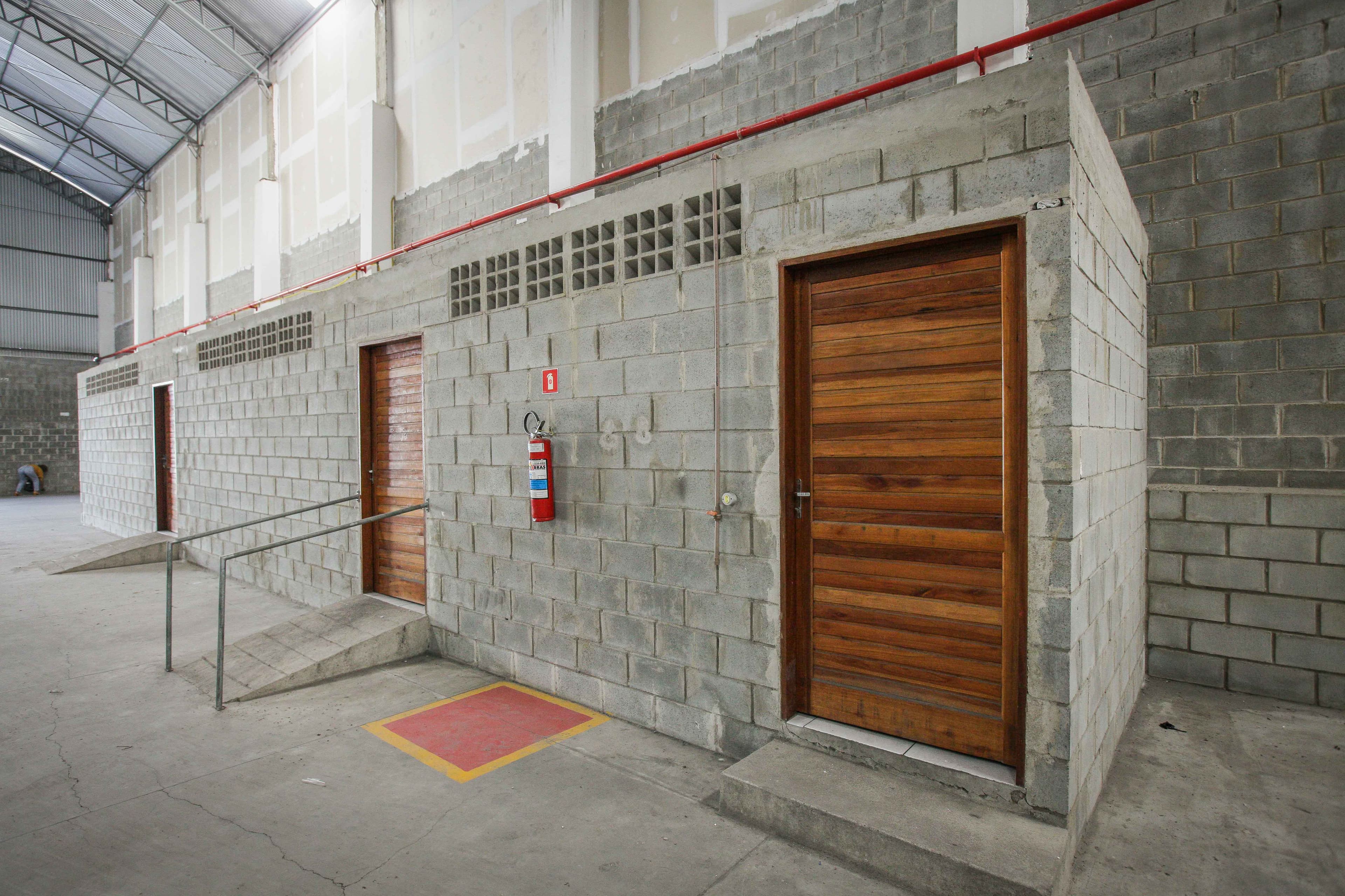 Portas dos vestiários vistas de perto, com piso tátil e rampa