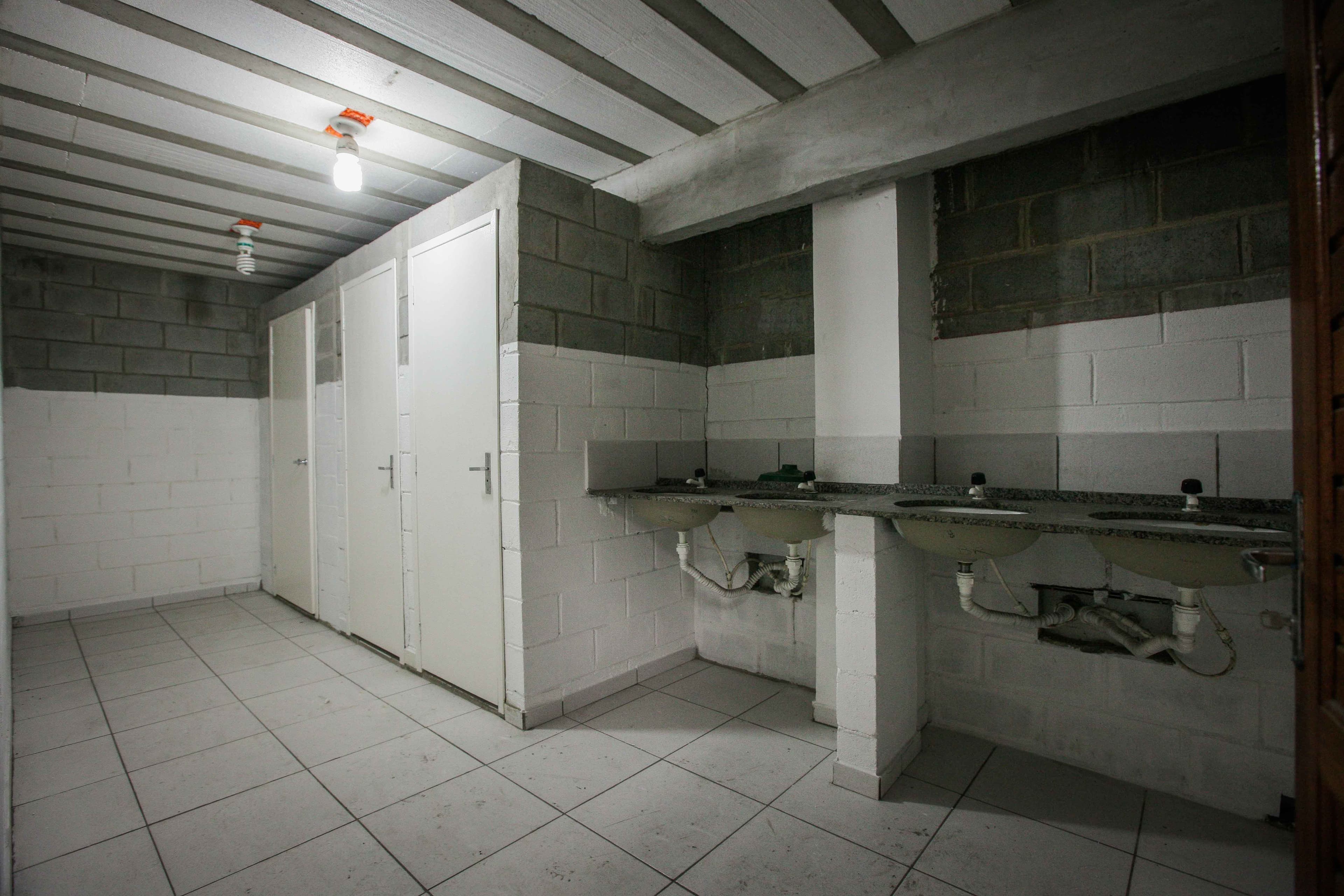 Lavatório coletivo com bancada e duas cubas, ao lado do vestiário